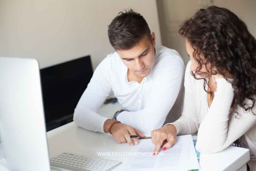 A man and a woman sitting at a desk reviewing a document together.