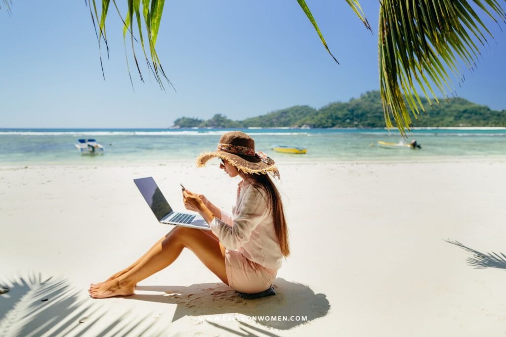 A women freelancer working on a beach sitting on a laptop.
